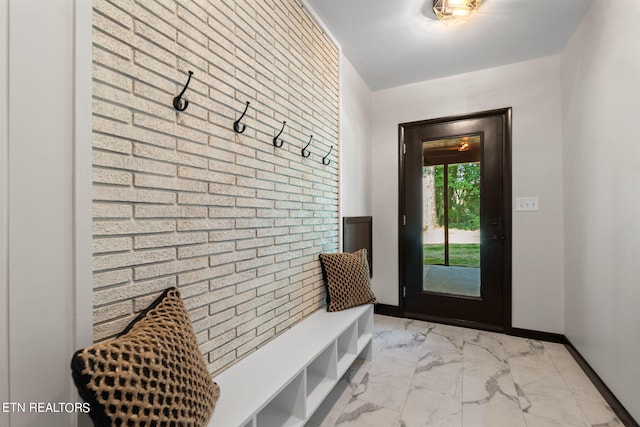 mudroom with brick wall and light tile patterned floors