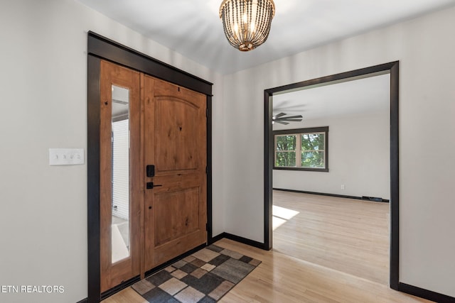 foyer entrance with ceiling fan with notable chandelier and light hardwood / wood-style floors