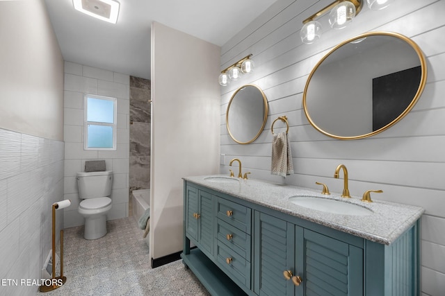 full bathroom with vanity, toilet, tile walls, and shower / washtub combination