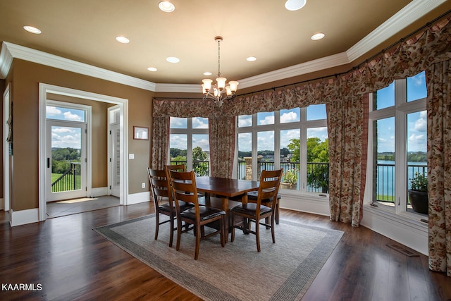 dining area with dark hardwood / wood-style flooring, a wealth of natural light, a water view, and crown molding