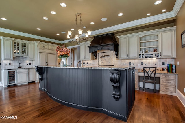 kitchen featuring wine cooler, a kitchen island with sink, dark wood-type flooring, hanging light fixtures, and custom range hood