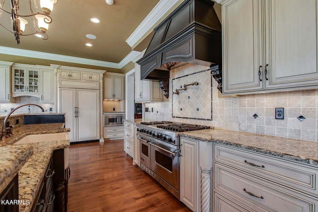 kitchen featuring premium range hood, ornamental molding, decorative light fixtures, dark wood-type flooring, and built in appliances