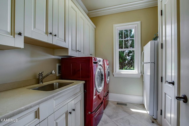 clothes washing area with light tile patterned flooring, crown molding, cabinets, washer and clothes dryer, and sink