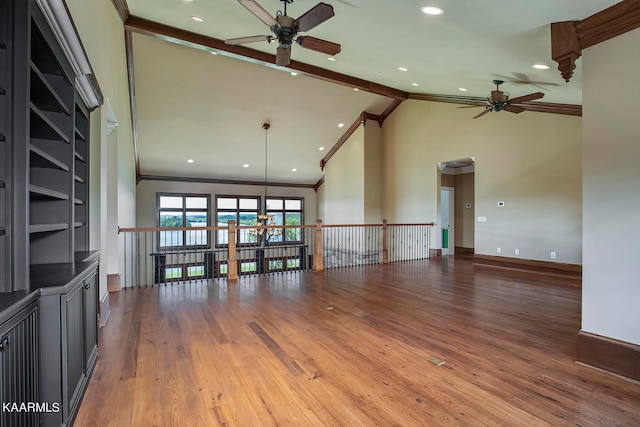 unfurnished living room with ornamental molding, wood-type flooring, vaulted ceiling with beams, and ceiling fan