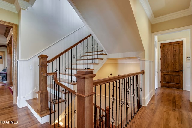 stairway with ornamental molding and hardwood / wood-style flooring