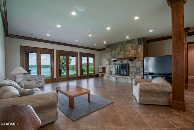 living room with ornamental molding, a water view, tile patterned floors, and a stone fireplace