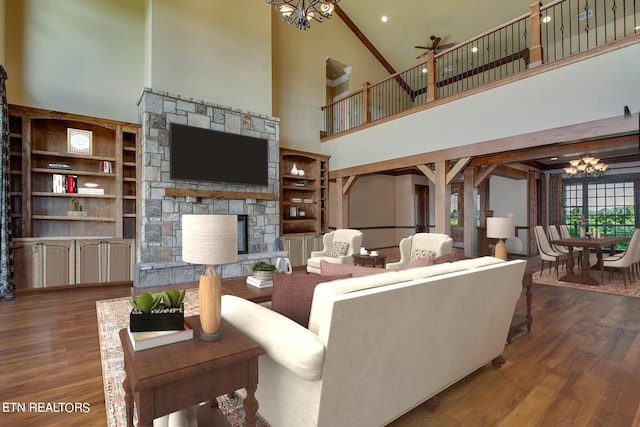 living room featuring hardwood / wood-style flooring, a stone fireplace, ceiling fan with notable chandelier, and high vaulted ceiling