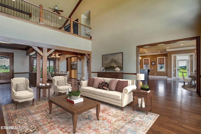 living room with wood-type flooring, ceiling fan with notable chandelier, a towering ceiling, and ornamental molding