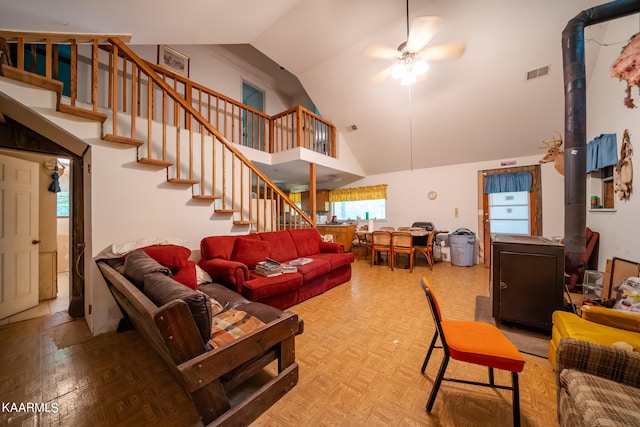 living room with lofted ceiling, light parquet floors, ceiling fan, and a wood stove