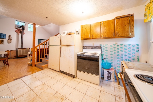 kitchen with light tile floors, a wood stove, white appliances, and a textured ceiling