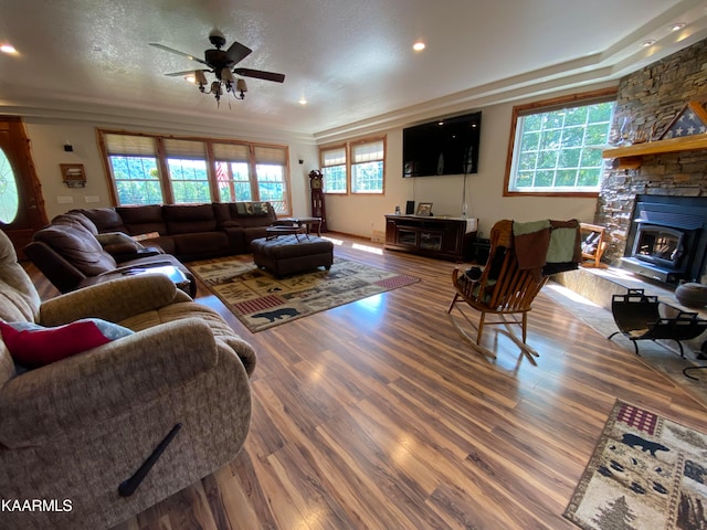 living room featuring ceiling fan, hardwood / wood-style floors, a textured ceiling, and a fireplace