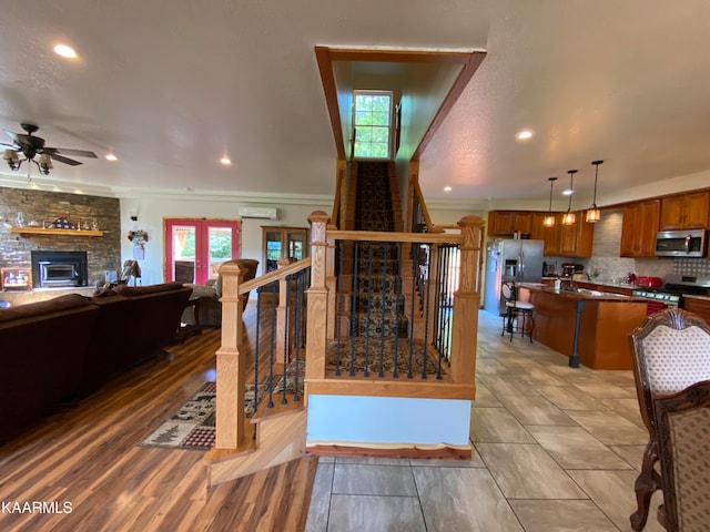 stairway featuring ceiling fan, a wealth of natural light, hardwood / wood-style floors, and a wall mounted AC