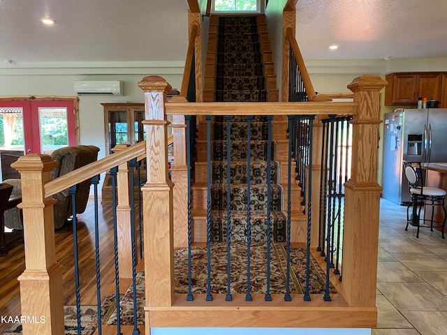 stairway featuring a textured ceiling, a wall unit AC, french doors, and tile patterned flooring