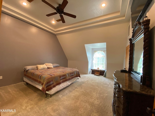 carpeted bedroom featuring ceiling fan, a raised ceiling, and vaulted ceiling