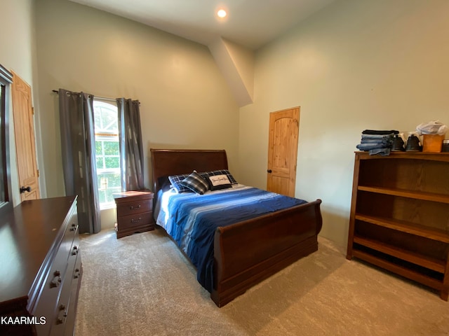 bedroom with high vaulted ceiling and light colored carpet