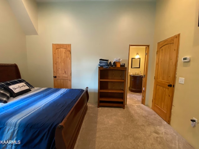 carpeted bedroom featuring a towering ceiling and ensuite bath