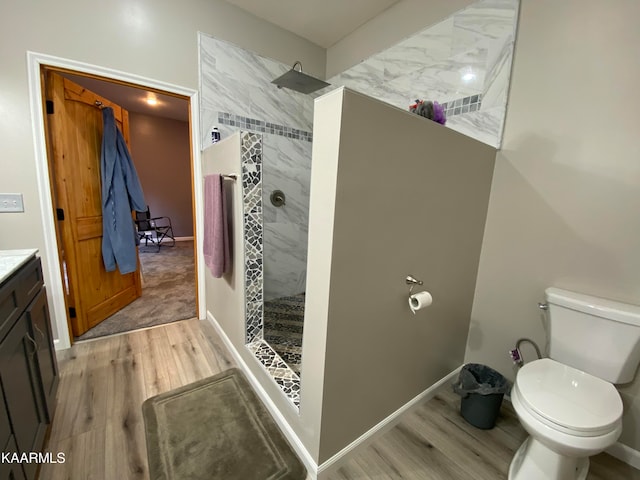 bathroom featuring toilet, vanity, tiled shower, and hardwood / wood-style flooring