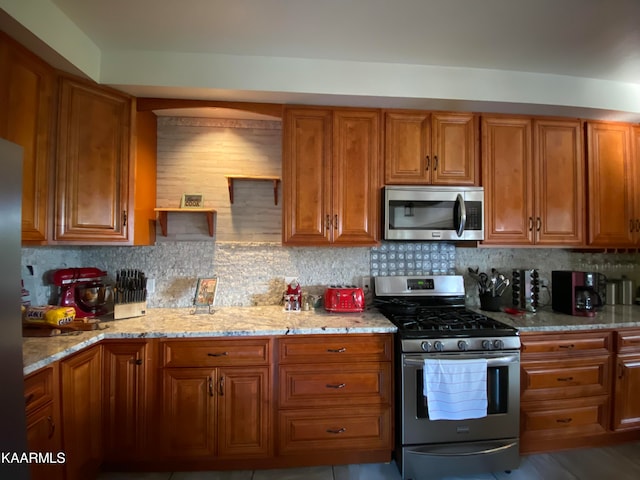 kitchen featuring light stone counters, backsplash, and appliances with stainless steel finishes