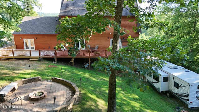 back of house featuring french doors, a wooden deck, a patio, a yard, and a fire pit