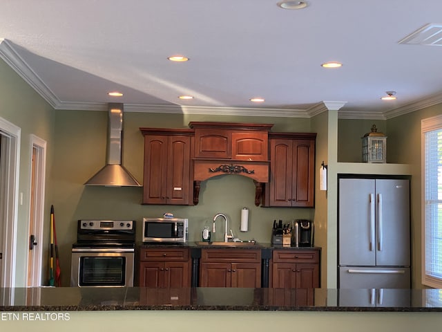 kitchen featuring wall chimney exhaust hood, dark stone counters, stainless steel appliances, and ornamental molding