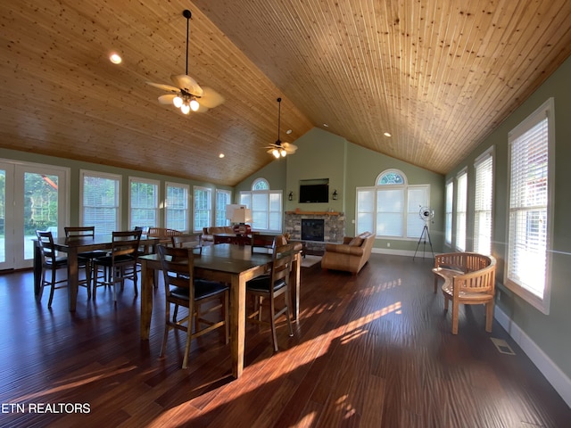 dining space with wooden ceiling, dark hardwood / wood-style flooring, a stone fireplace, and ceiling fan