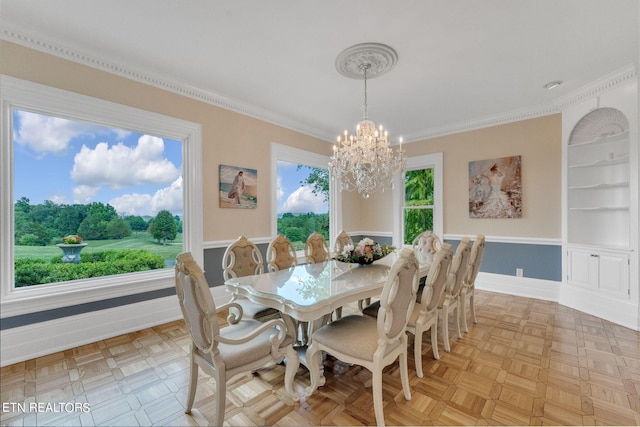 dining area with light parquet floors, ornamental molding, and an inviting chandelier