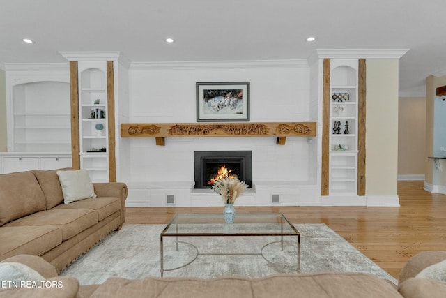 living room featuring built in features, ornamental molding, and light hardwood / wood-style flooring