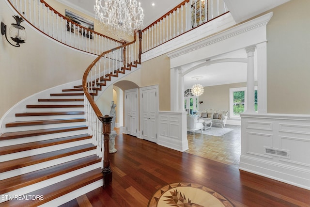 entryway featuring a high ceiling, dark hardwood / wood-style flooring, decorative columns, and a notable chandelier