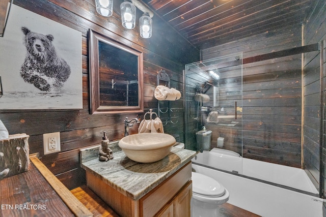 full bathroom with vanity, wooden walls, shower / bath combination with glass door, wooden ceiling, and toilet