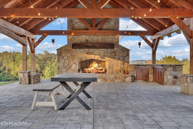 view of patio with an outdoor stone fireplace and an outdoor kitchen