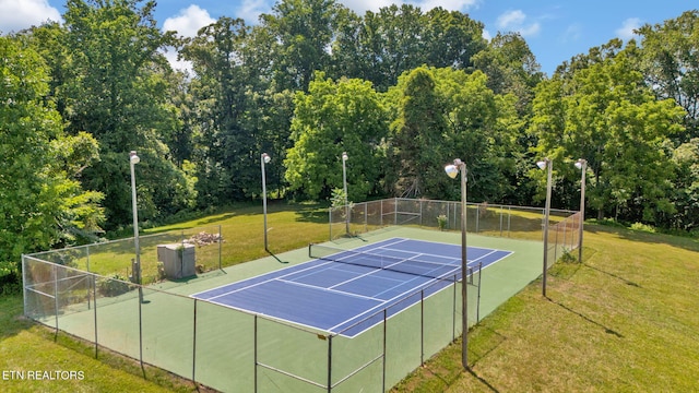 view of tennis court featuring basketball hoop and a yard