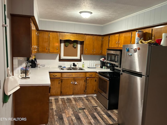 kitchen with appliances with stainless steel finishes, dark hardwood / wood-style floors, sink, a textured ceiling, and ornamental molding