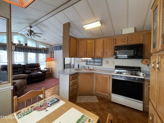 kitchen featuring ceiling fan, lofted ceiling, dark parquet flooring, kitchen peninsula, and gas range