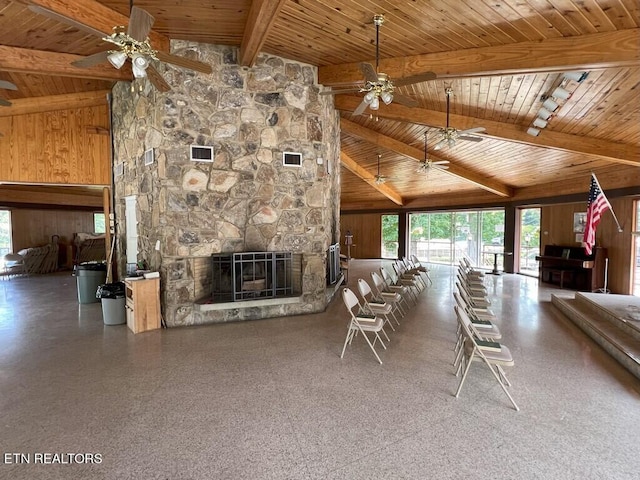 unfurnished living room with a stone fireplace, wooden walls, rail lighting, lofted ceiling with beams, and wooden ceiling