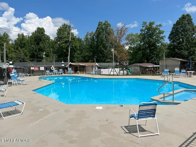 view of pool featuring a playground and a patio area