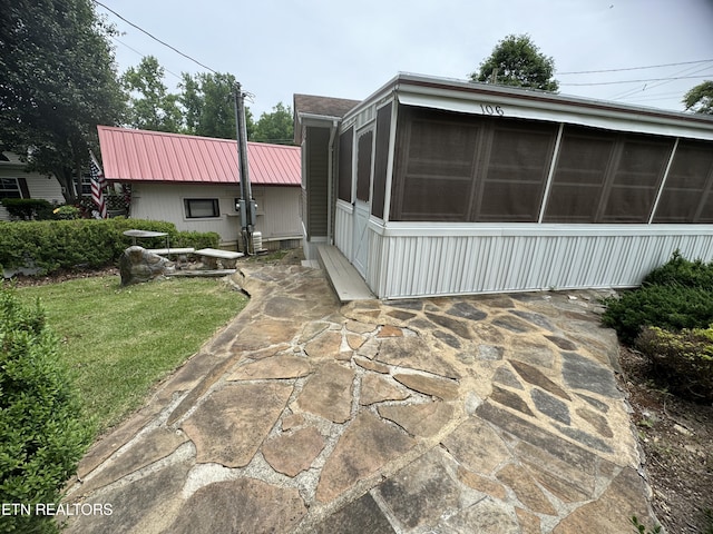 view of side of property with a sunroom, a lawn, and a patio