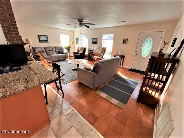 living room with ceiling fan, brick wall, and light hardwood / wood-style flooring