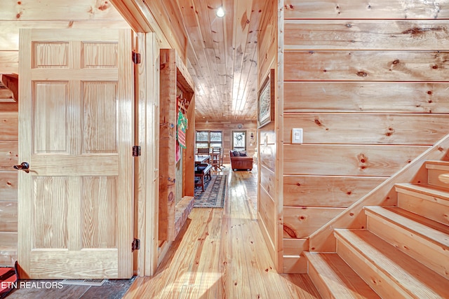 hall featuring wooden ceiling, light hardwood / wood-style flooring, and wooden walls