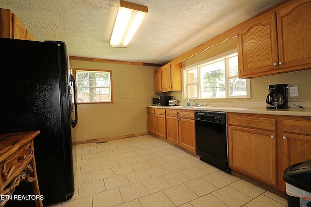 kitchen featuring light tile floors, a textured ceiling, black appliances, and a healthy amount of sunlight