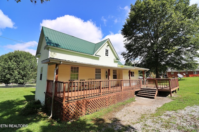 back of property featuring a wooden deck and a yard