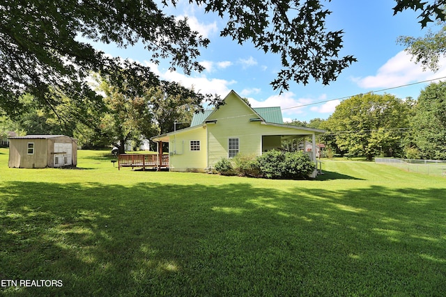 back of property with a yard, a deck, and a shed