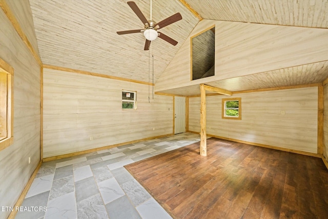 spare room with light tile flooring, wooden walls, ceiling fan, and high vaulted ceiling