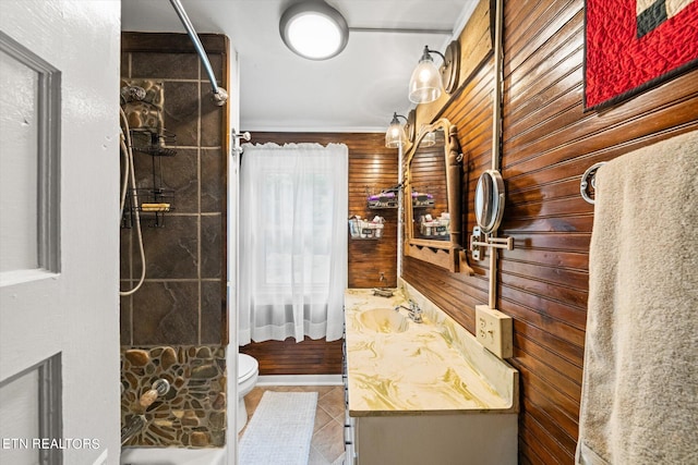 bathroom featuring wooden walls, tile flooring, toilet, and vanity