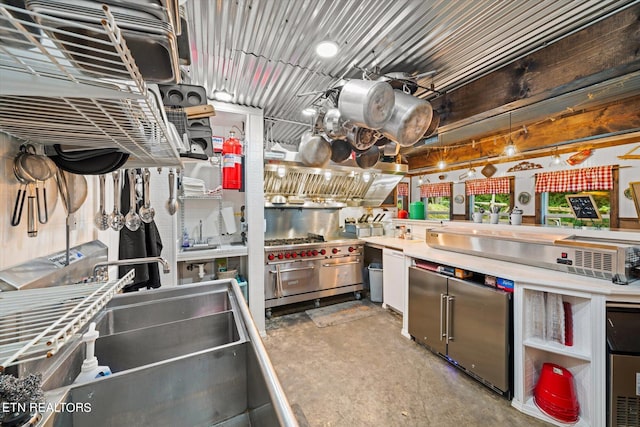 kitchen with fridge, double oven range, sink, and stainless steel counters