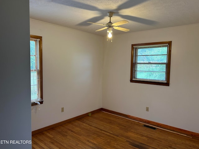 spare room with a healthy amount of sunlight, hardwood / wood-style floors, ceiling fan, and a textured ceiling