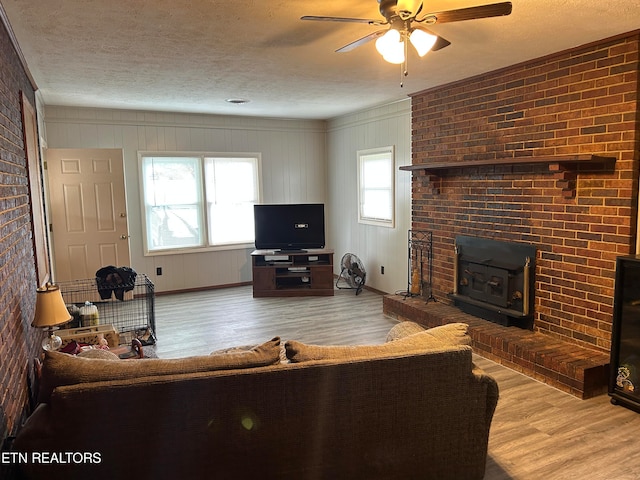 living room featuring a fireplace, light hardwood / wood-style flooring, ceiling fan, and plenty of natural light