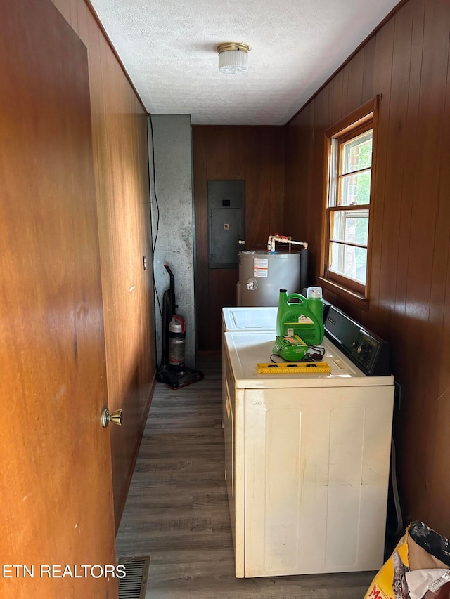 clothes washing area with dark hardwood / wood-style flooring, wood walls, electric water heater, washer and dryer, and a textured ceiling