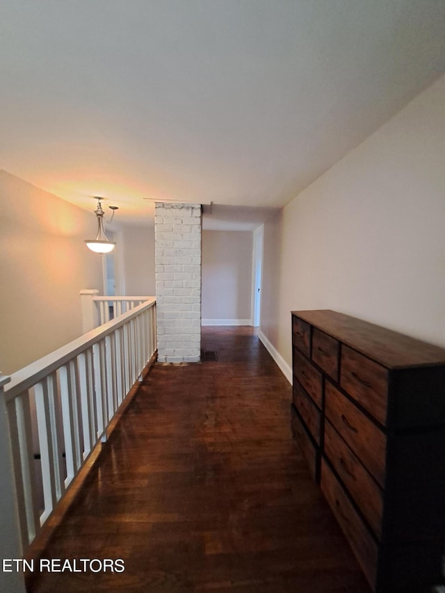 corridor with dark hardwood / wood-style flooring and brick wall