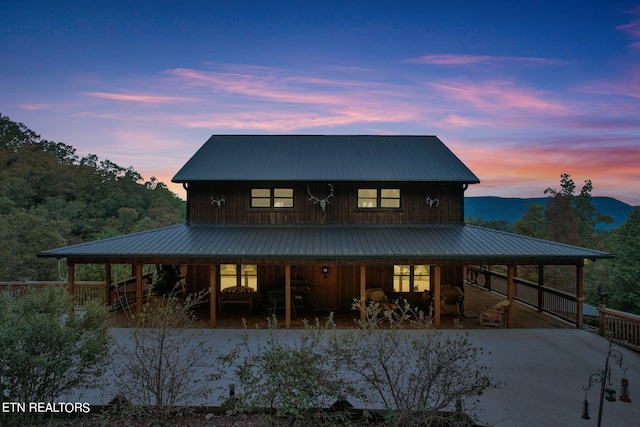 back house at dusk featuring a porch