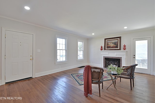 living area featuring crown molding, a fireplace, baseboards, and wood finished floors